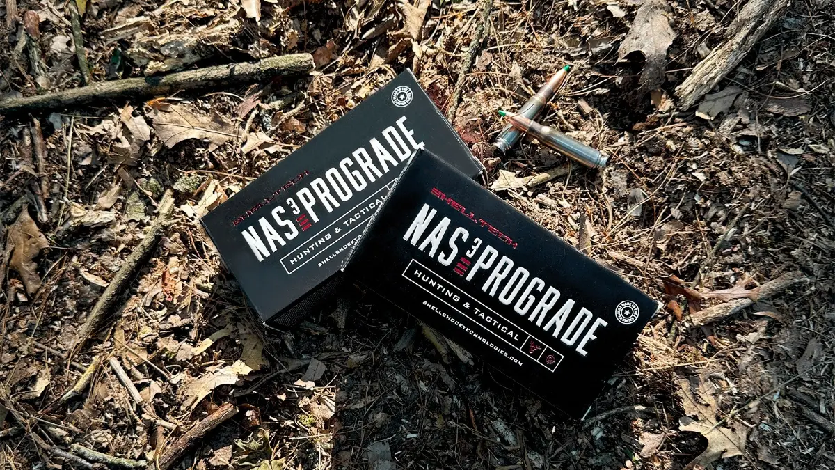 Two boxes of Shell Tech 308 NAS³ PROGRADE on dirt with two loaded bullets