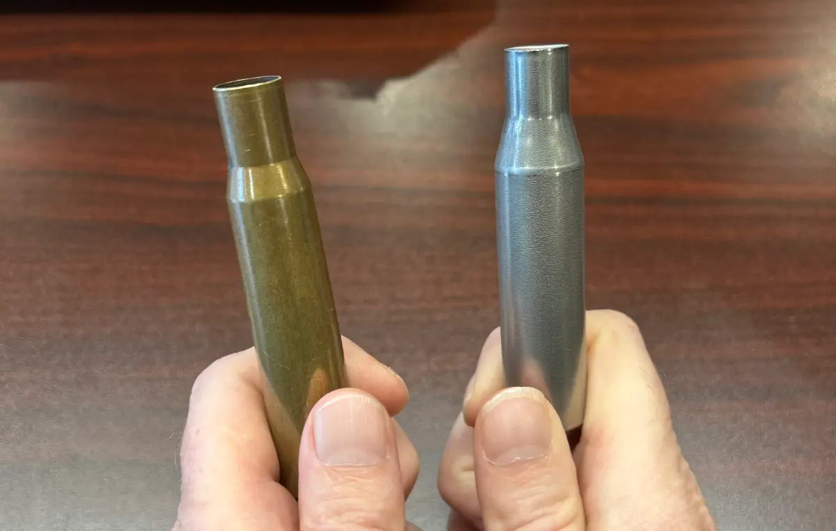 NAS³ .50 BMG nickel-stainless steel alloy cartridge case beside a traditional brass .50 BMG case